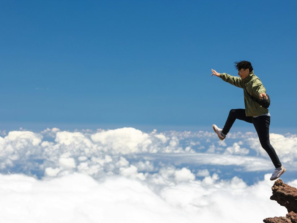 a man jumping off a cliff into the sky