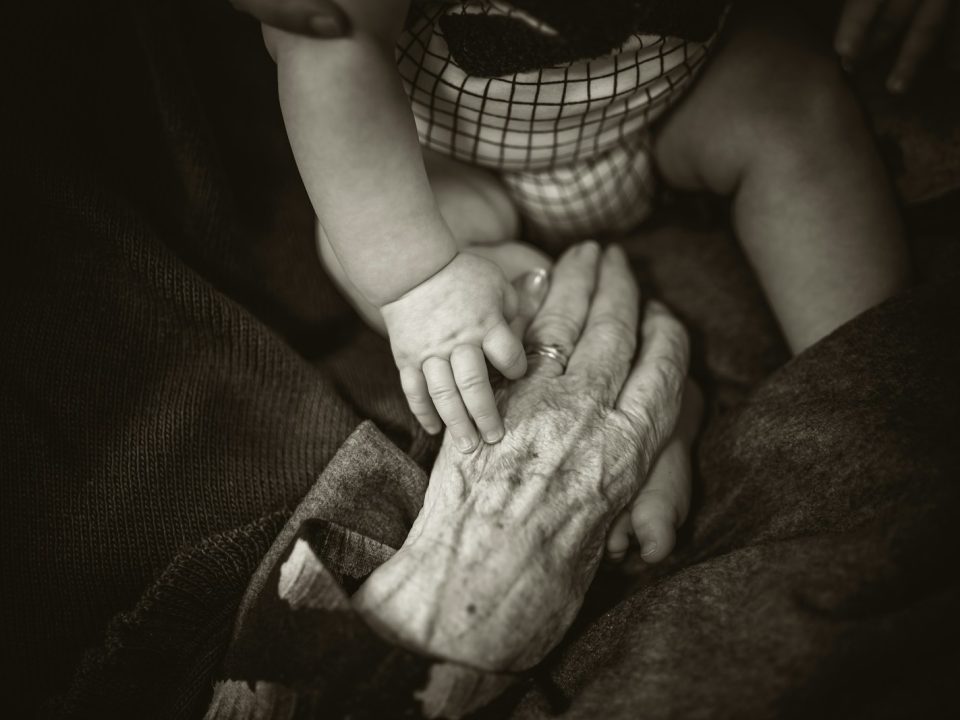 an older woman holding a baby's hand