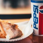 a piece of bread and a cup of pepsi on a table