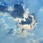 The sun is shining through the clouds in the sky