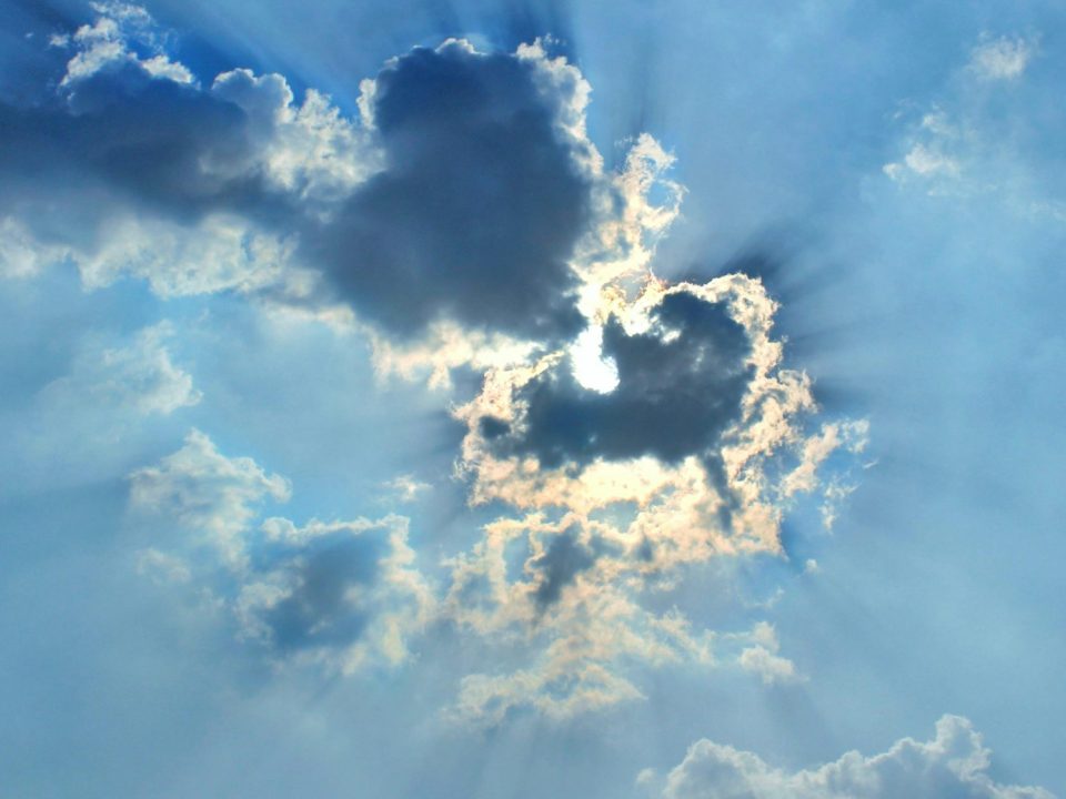 The sun is shining through the clouds in the sky